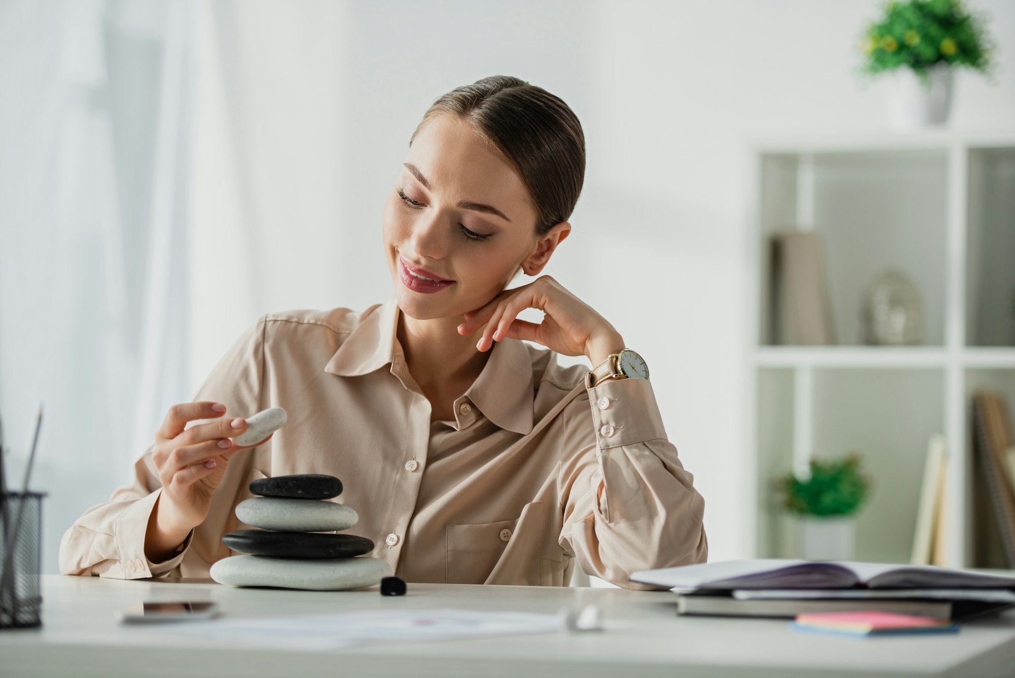 happy businesswoman sitting at workplace with zen stones
